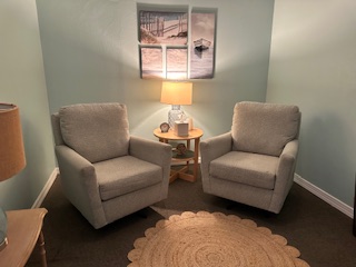 Peaceful therapy room with matching chairs and beach artwork at Estero office